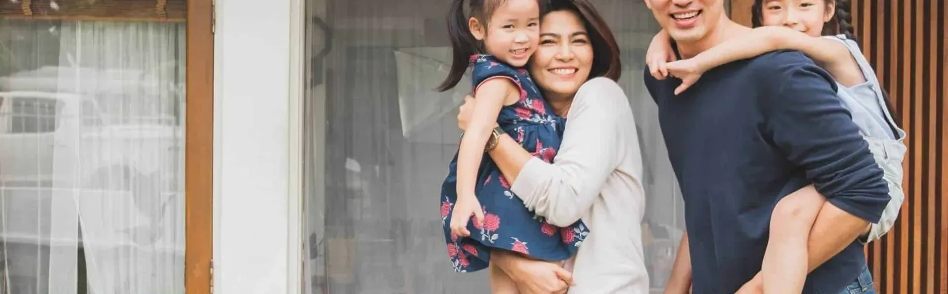 A young family with two children at the front door of their home